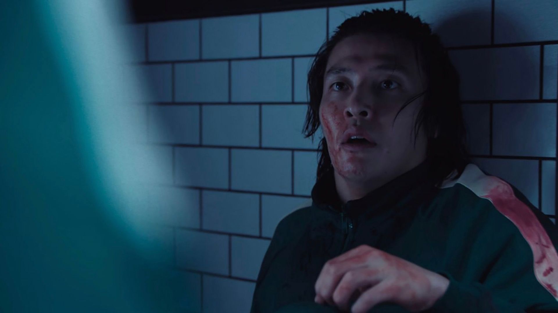 Dae-ho crouched in a corner, covered in blood in Squid Game.
