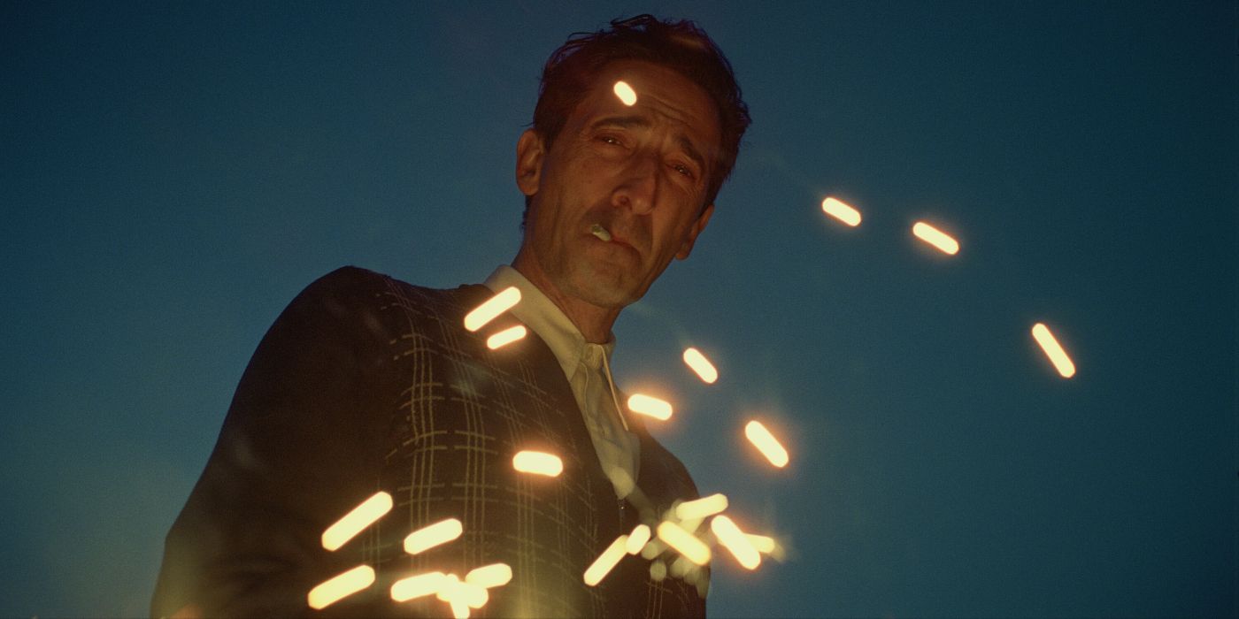 Adrien Brody as Laszlo stands by a sparkler in The Brutalist
