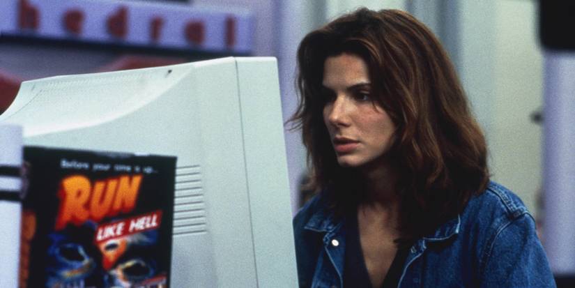 Sandra Bullock sitting in front of a computer in a blue jean jacket in The Net