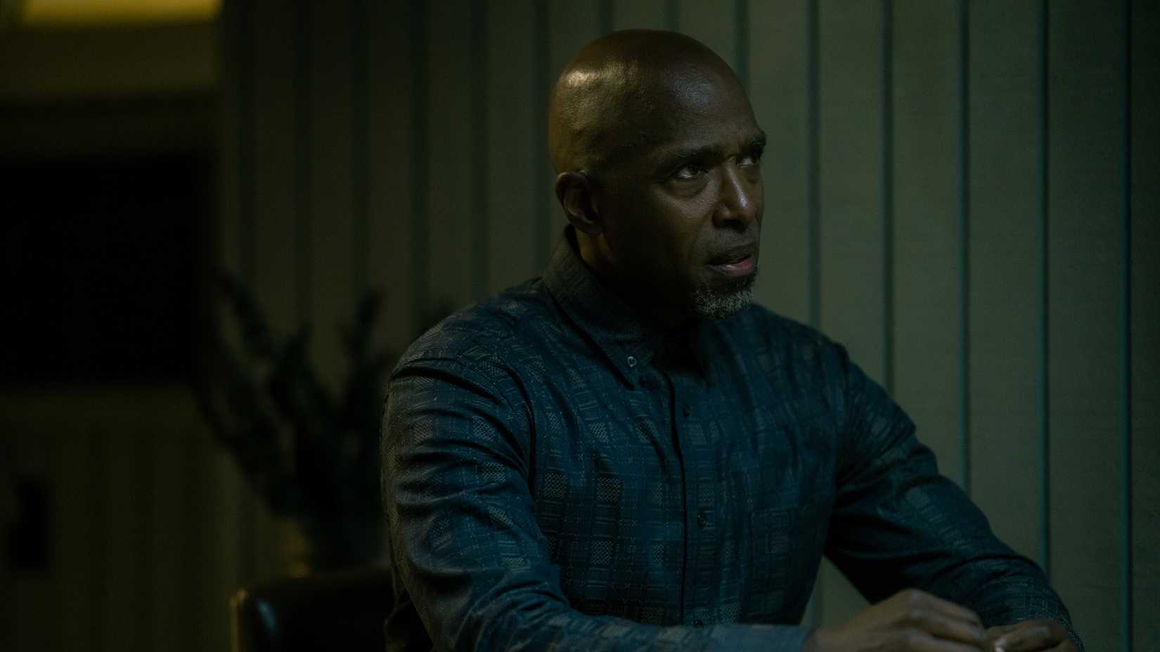 Blessing sitting at a table looking angry in Dexter: Resurrection.