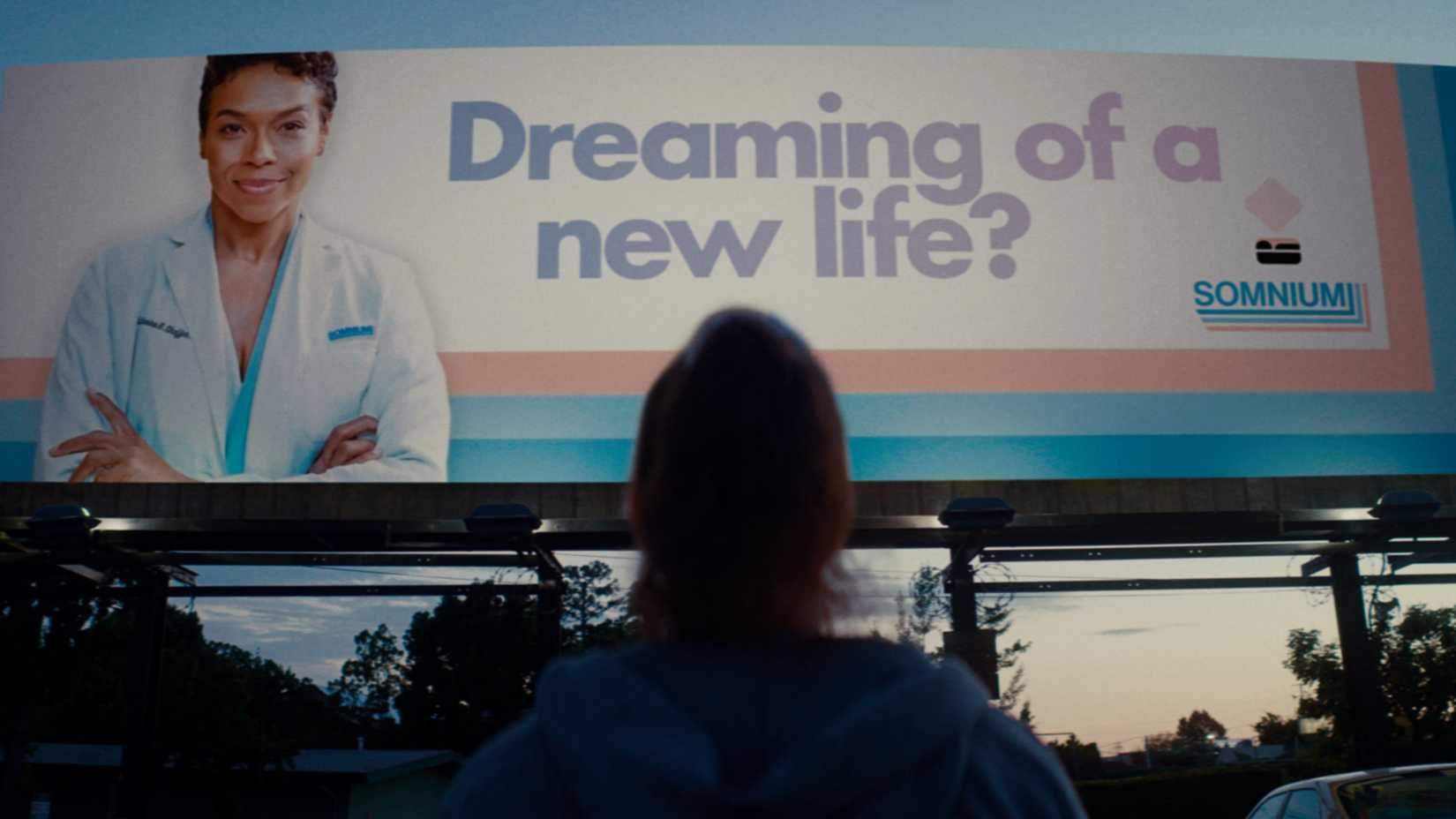 Chloë Levine standing in front of a billboard featuring Gillian White in Racheal Cain's 'Somnium'