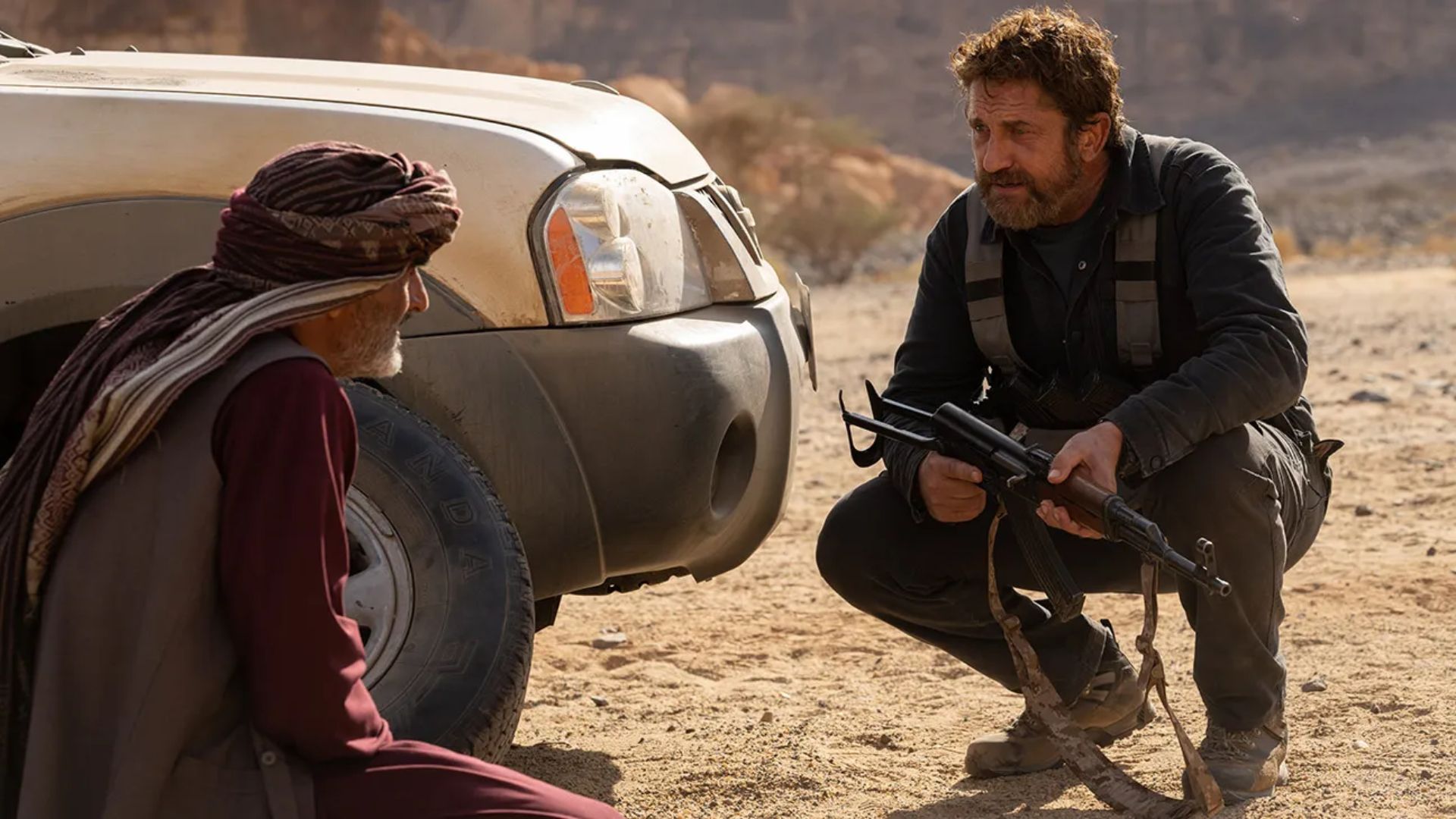Tom Harris helping Mo to change a tire in the desert in 2023's Kandahar