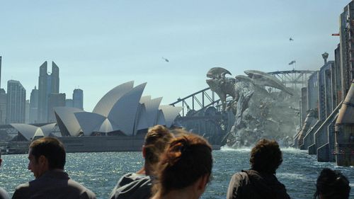 People watch in horror as a Kaiju destroys this Australian landmark{69}: We talked a lot about the development about these characters. About how the Jaegers would move, how the Kaiju would move, and one of the things that we talked about at the beginning was possibly using motion capture to drive some of the forms of the creatures. But we decided against that for a couple reasons. One thing that we're dealing with a lot is scale. Our creatures are very big. Our robots, or Kaiju, are 260 feet hig
