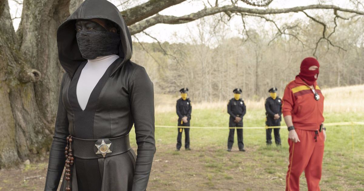 Cops and superheroes stand by a tree in Watchmen