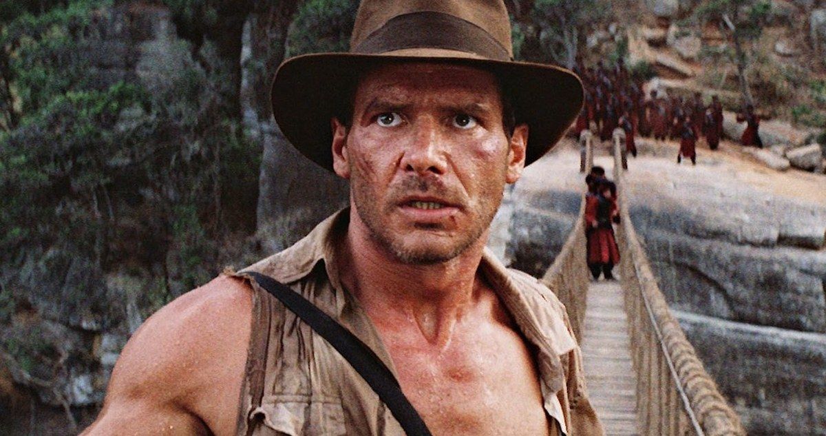 Shirtless Indiana Jones, still wearing a hat, on a bridge
