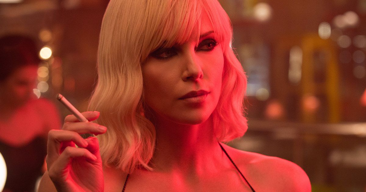 Charlize Theron holds a cigarette in red lighting in Atomic Blonde
